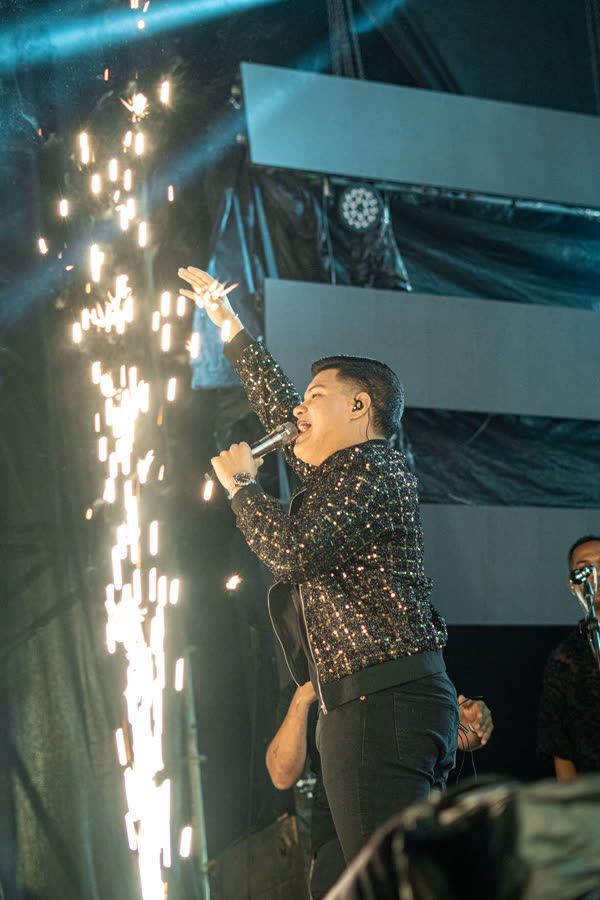 Cantante en tarima junto a una columna de chispa fría.